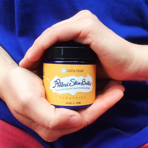 4 ounce jar of tangerine hand cream cradled by hands