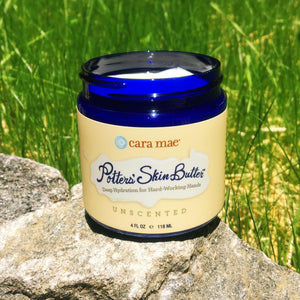 4 ounce jar of unscented hand cream outside on a sunny rock with grass in the background